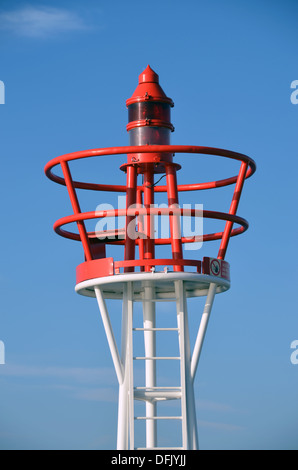 Un rosso e bianco faro di luce contro il cielo blu nel porto di Cherbourg, la Normandia. Foto Stock