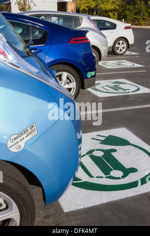 EV simbolo dipinto su spazi di parcheggio presso una società parcheggio indicando le macchie sono riservati per il plug-in di auto elettriche Foto Stock