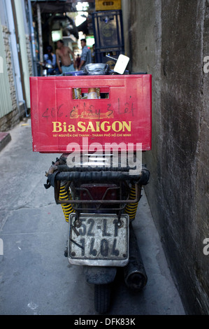 Bia (Saigon Saigon birra) cassa sul retro di una moto parcheggiata in un vicolo a Saigon, Vietnam Foto Stock