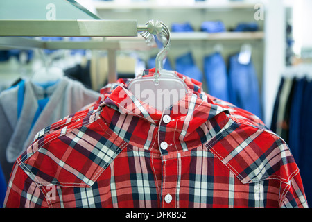 Close-up di camicetta, maglietta sulla stampella. Rack, vestiti colorati. Fashion in store, negozio. Foto Stock