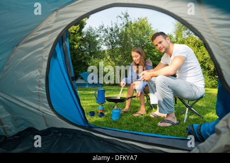 Una giovane coppia la cottura nella parte anteriore di una tenda Foto Stock