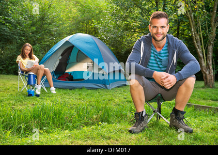 Una giovane coppia rilassarsi di fronte ad una tenda Foto Stock