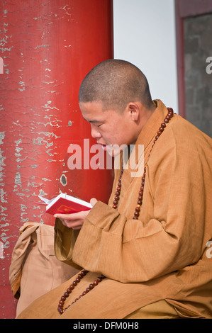 Giovane monaco buddista pregando in Wanchun ting Pavilion (Padiglione dell'eterna primavera) nel Parco Jingshan, Pechino, Cina Foto Stock