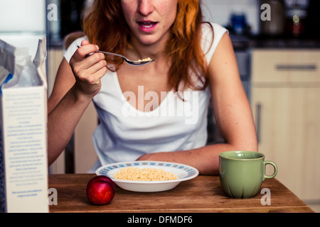 Donna con cereali e pesca per la prima colazione Foto Stock