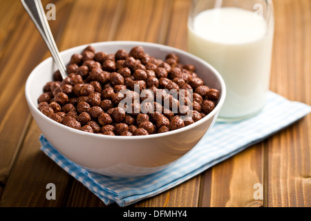 Cereali di cioccolata in tazza e latte sul tavolo di legno Foto Stock