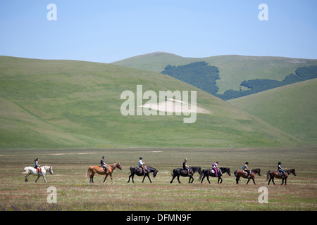 Cavalieri di equitazione in spazio aperto, paesaggio, Castelluccio di Norcia in Umbria, Italia, Europa Foto Stock