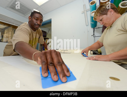 Il sig. Antoine Robinson, e tecnico Sgt. Tracy Davis della 436th Manutenzione aeromobili squadrone, controllo della corrosione shop, opera su un adesivo vinilico che sarà usato per mascherare un'area durante la verniciatura sul Sett. 9, 2013 Alla Dover Air Force Base, Del. La sezione è Foto Stock