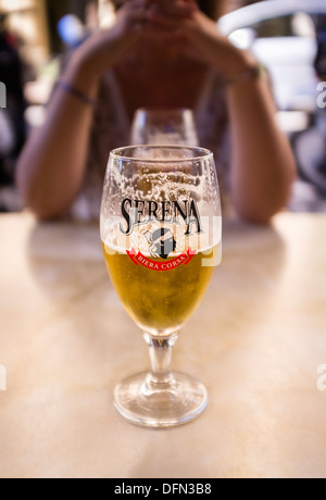 Mezzo bicchiere pieno di birra su di una tavola di ristorante Foto Stock