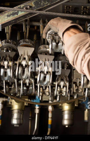 Senior Airman Zac Sidders, 774th Airlift Expeditionary Squadron C-130 Hercules loadmaster, afferra il tirante verso il basso dispositivi a catena per un 10.000 pound carrello in avanti una base operativa Sharana, Provincia Paktika, Afghanistan, Sett. 28, 2013. Questa missione ha segnato una Foto Stock