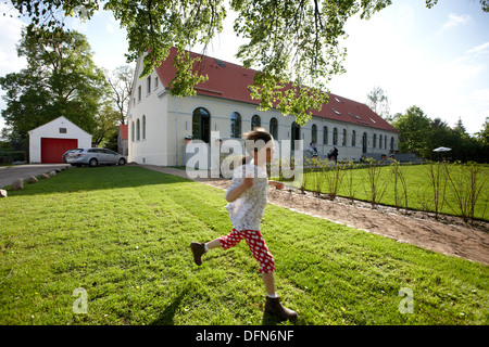 Ragazza che corre su un prato vicino ad un hotel, Fincken, Meclemburgo-Pomerania, Germania Foto Stock