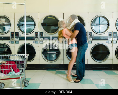 Una donna graziosa abbracci da una smart Giovane in San Diego lavanderia a gettone. Foto Stock