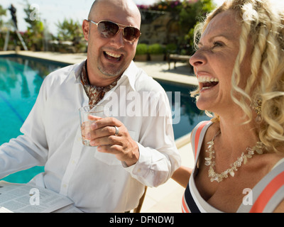 Un giovane uomo si gode il suo drink con una bella donna dal lato di una piscina in San Diego. Foto Stock