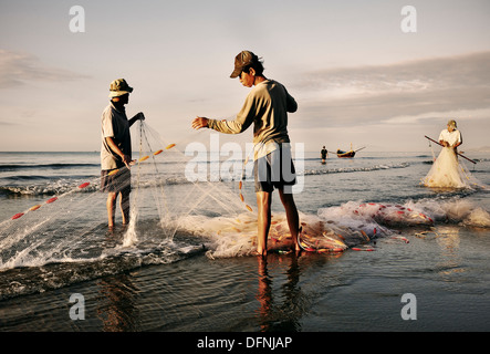 I pescatori della piegatura delle loro reti sulla spiaggia dopo il lavoro, Mui Ne villaggio di pescatori, Vietnam, sul Mare della Cina del Sud Foto Stock