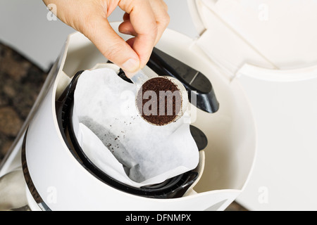 Angolo orizzontale foto di sesso femminile mettendo mano caffè fresco motivi in bianco sbiancato filtro per caffè con caffè e pietra Foto Stock