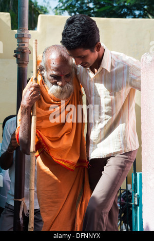 Vecchio sadhu indiano essendo aiutato nello Sri Sathya Sai Baba outreach mobile hospital Clinic. Andhra Pradesh, India Foto Stock