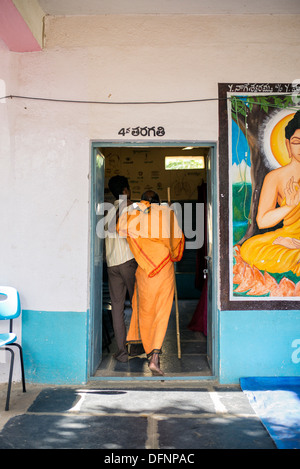 Vecchio sadhu indiano essendo aiutato nello Sri Sathya Sai Baba outreach mobile hospital Clinic. Andhra Pradesh, India Foto Stock