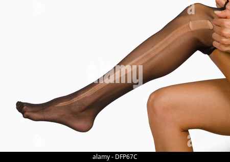 Prendere di un collant strappati sulle gambe femmina Foto Stock