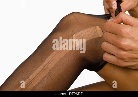 Prendere di un collant strappati sulle gambe femmina Foto Stock
