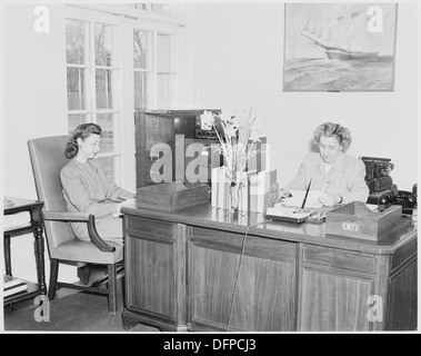 Una fotografia che cattura Rose Conway, la segretaria del presidente Harry S. Truman, seduta alla sua scrivania alla Casa Bianca, con una donna non identificata presente. Questa immagine rappresenta l'ambiente amministrativo dell'ufficio durante la presidenza di Truman. Foto Stock