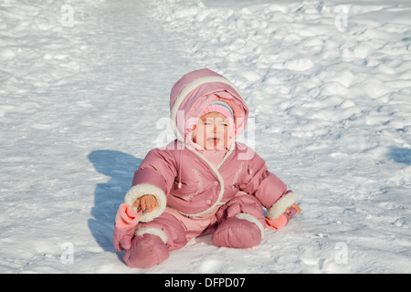 La bambina grida seduti sulla neve Foto Stock