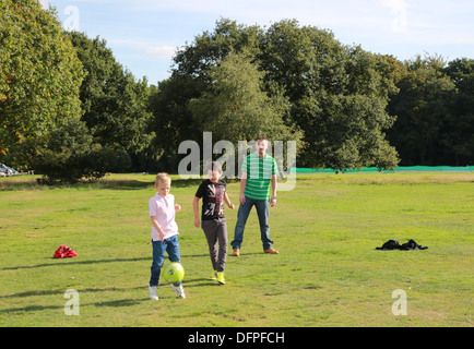 Padre e figli a giocare a calcio nel parco, REGNO UNITO Foto Stock