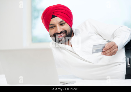 La religione sikh uomo facendo shopping online con una carta di credito Foto Stock