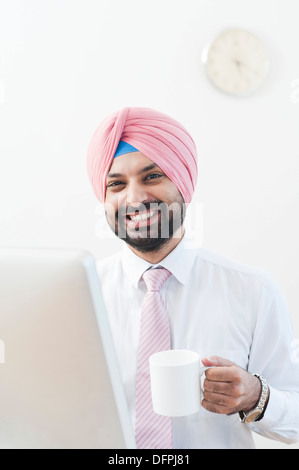 Imprenditore a bere caffè e sorridente Foto Stock