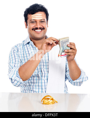 Ritratto di un sud indiane uomo conteggiare denaro e sorridente Foto Stock