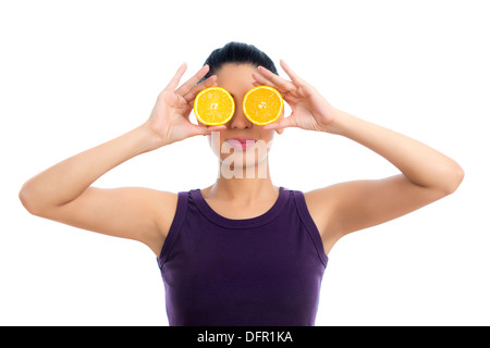 Donna che mantiene le metà arancione oltre i suoi occhi Foto Stock