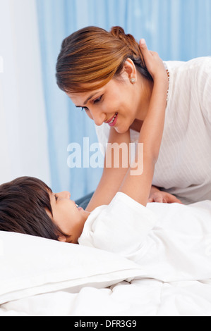 Ragazzo abbraccia il suo madre sul letto Foto Stock