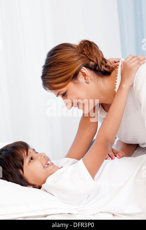 Ragazzo abbraccia il suo madre sul letto Foto Stock