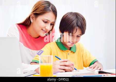 La donna che assiste il suo figlio a disegno Foto Stock