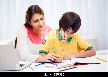 La donna che assiste il suo figlio a disegno Foto Stock