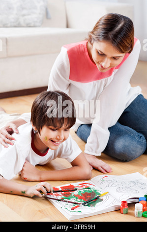 Ragazzo facendo la colorazione con sua madre seduta accanto a lui Foto Stock