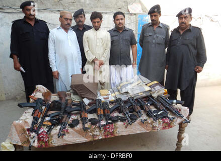 Accise i funzionari di polizia sono mostra sequestrati armi e droghe che recuperato durante il raid su un carrello in movimento a Karachi dal a Peshawar, a Ubauro Martedì, Ottobre 08, 2013. La polizia di accise recuperato un numero di pistole di macchina, vicino a circa cinque giri migliaia e quaranta chili di Charas Foto Stock