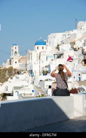 SANTORINI (THIRA), cicladi grecia. Un vacanziere fotografando la pittoresca scogliera-top villaggio di Imerovighli vicino a Fira. Foto Stock