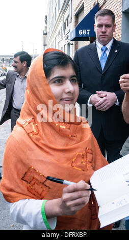 New York, Stati Uniti d'America. 08 ott 2013. Malala Yousafzai schoolgirl pakistano attivista di istruzione delle pause per firmare copie del suo libro, "io sono Malala: La ragazza che si alzò per istruzione e fu ucciso dai talebani", come lei arriva per comparsa sul Daily Show con Jon Stewart. La città di New York, Martedì, 8 ottobre 2013, STATI UNITI D'AMERICA. Credito: Dorothy Alexander/Alamy Live News Foto Stock