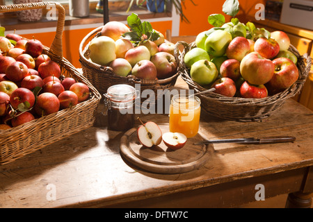 Mele, diverse varietà in ceste, disposti su una tavola con miele e marmellata Foto Stock