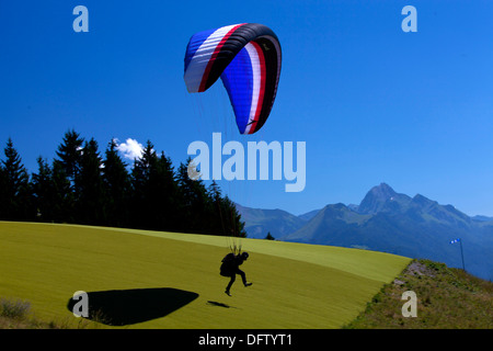 Pilota di parapendio decolla da un ambiente alpino in Haute Savoie regione vicino a Annecy in Francia Foto Stock