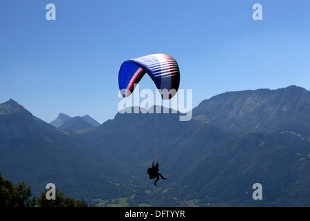 Un parapendio in volo su una valle alpina in Haute Savoie regione vicino a Annecy, Francia Foto Stock