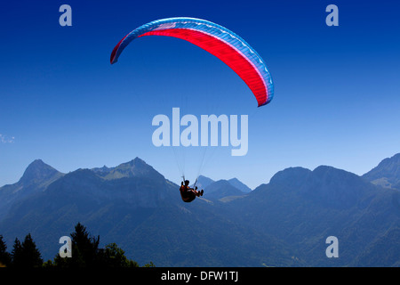 Para pilota di parapendio volare il suo paracadute sopra le montagne Foto Stock