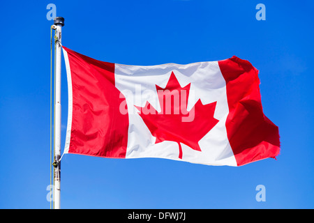 Bandiera canadese su un flagpole contro uno sfondo blu cielo senza nuvole bandiera canadese rockies canada Foto Stock