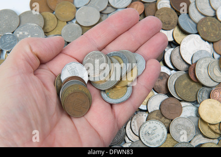 Varie monete con alcune in una mano Foto Stock
