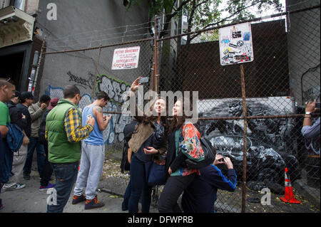 New York City, NY, STATI UNITI D'AMERICA. 09oct, 2013. Gli appassionati di graffiti gregge di una partita vacante nel quartiere di Lower East Side di New York il Mercoledì, Ottobre 9, 2013 per vedere la nona puntata di Banksy graffiti dell'arte. Questo particolare rata viene visualizzato attraverso una catena collegamento recinto e un recinto bloccato. Credito: Francesca Roberts/Alamy Live News Foto Stock