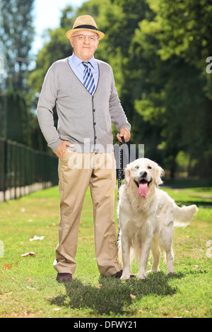 Senior l uomo e il suo cane in posa di un parco Foto Stock