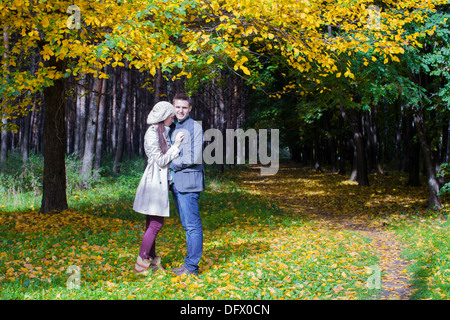 Coppia giovane in amore sul grande prato in autunno sotto grandi alberi di acero in autunno soleggiata giornata Foto Stock