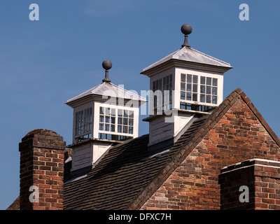 Due vecchie rettangolare vetri decorati piccoli colombai al di sopra di tegole rosse e tetto a spiovente, Calke Abbey, Ticknall, Derbyshire, England, Regno Unito Foto Stock