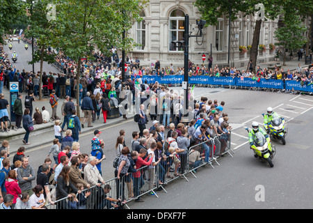 Gli spettatori guardano su come la polizia outriders portano i piloti attraverso le strade di Londra durante il tour della Gran Bretagna cycle race, 2013 Foto Stock