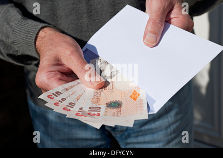 Primo piano di Man Hand che detiene banconote in denaro inglesi in contanti Banconota £10 banconote da 10 sterline e busta bianca Inghilterra UK Regno Unito GB Gran Bretagna Foto Stock