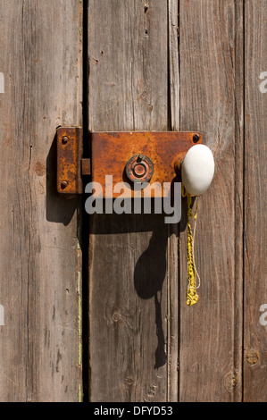 Una porta in legno antica con serratura in metallo e manico bianco. Foto Stock